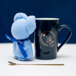 Black ceramic mug with a love motif and a blue teddy bear with a 'Just for you' ribbon on a blue background.