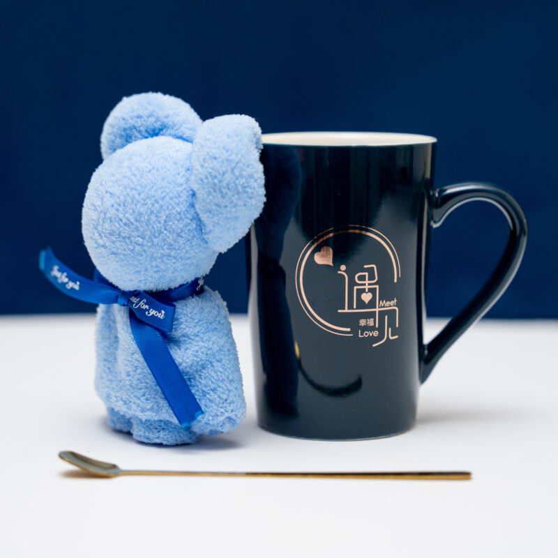 Black ceramic mug with a love motif and a blue teddy bear with a 'Just for you' ribbon on a blue background.