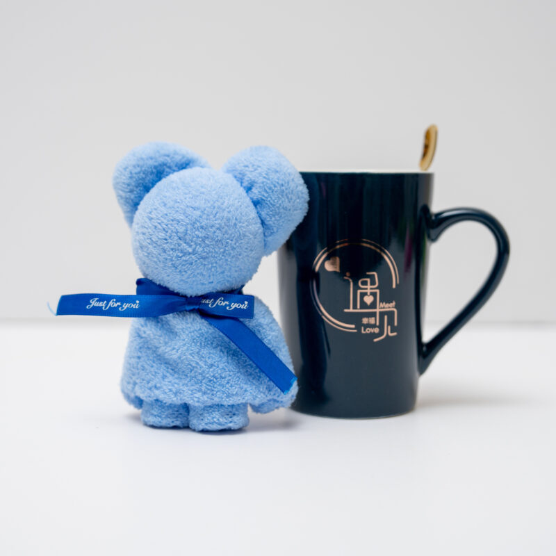 Black mug featuring a romantic design with a blue plush teddy bear and a golden spoon on a white background.