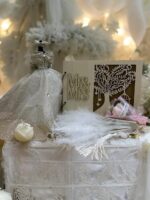 "Elegifta Wedding Gift Set featuring an elegant mini wedding dress, sophisticated feather hand fan, beautiful guest book for memories, luxurious silk rose pillow cases, stylish hair tie, whimsical satan eye mask, serene white flower candle, meaningful wedding heart message, charming mini bouquet, and fragrant natural rose soap."