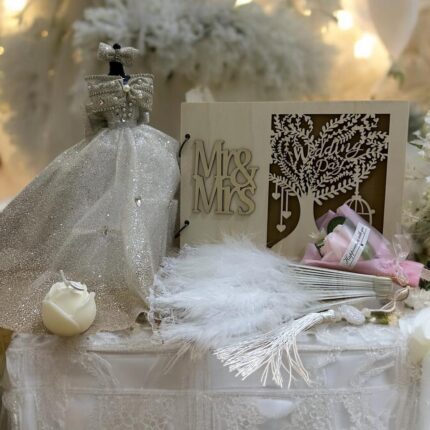 "Elegifta Wedding Gift Set featuring an elegant mini wedding dress, sophisticated feather hand fan, beautiful guest book for memories, luxurious silk rose pillow cases, stylish hair tie, whimsical satan eye mask, serene white flower candle, meaningful wedding heart message, charming mini bouquet, and fragrant natural rose soap."